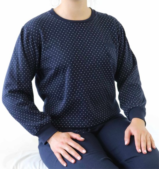 Vrouw in donkerblauwe pyjamaset met witte stippen, zittend, detail van de bovenkant.