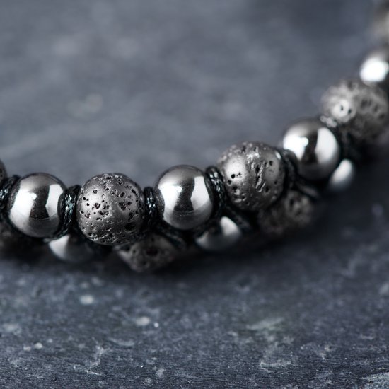 Gedetailleerde close-up van een dubbele armband met donkere, ruwe lavastenen en gladde, glanzende grijze kralen.