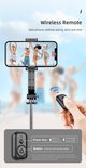 Drie vrouwen springen op de foto, genomen met een telefoon op een selfie-stick. Een hand houdt een draadloze afstandsbediening vast.