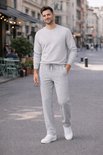 Man draagt grijze joggingbroek en lichtgrijze trui met ritskraag, witte sneakers in stad.
