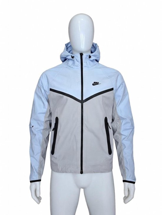 Lichtblauwe en grijze Nike trainingsjas met capuchon en ritssluiting. Zwart Nike logo op de borst.