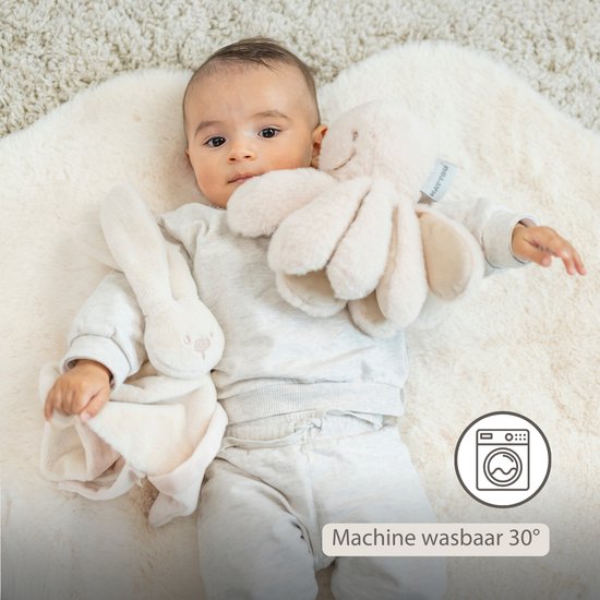 Baby ligt op een zachte ondergrond met een crèmekleurig konijnen knuffeldoekje. Wasbaar op 30 graden.