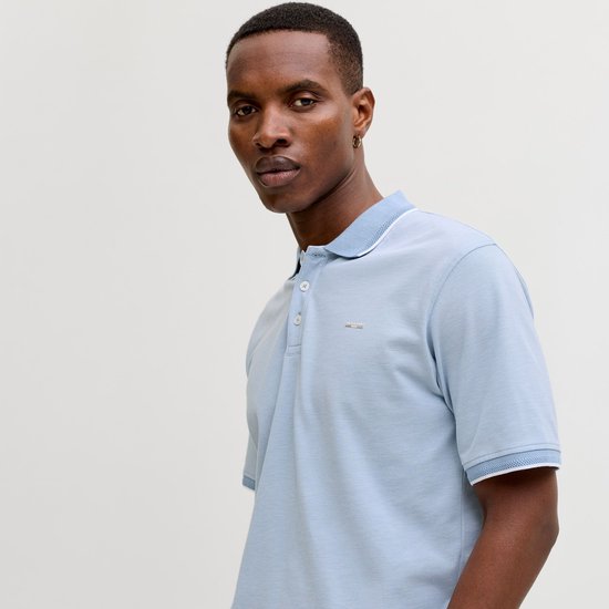 Man in lichtblauw poloshirt met witte kraag en manchetten.