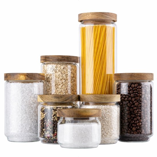 Ensemble de sept bocaux de stockage en verre avec couvercles en bois, remplis de sel, grains de poivre, flocons d'avoine, pâtes et grains de café.