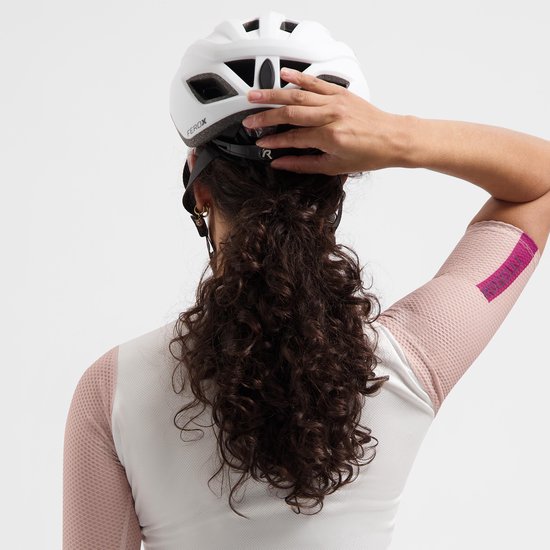 Vrouw draagt witte Rogelli fietshelm en witte trui met roze mesh mouwen. Achteraanzicht.
