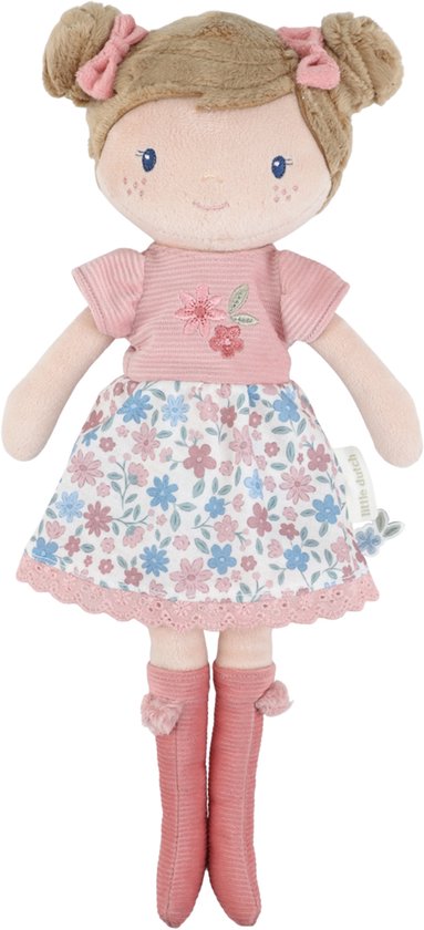 Poupée douce aux cheveux bruns en chignons avec nœuds, haut rose, jupe à fleurs et bottes roses.