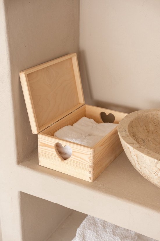Open houten kistje met hartvormige handvatten, met witte handdoeken erin, in een badkamer.