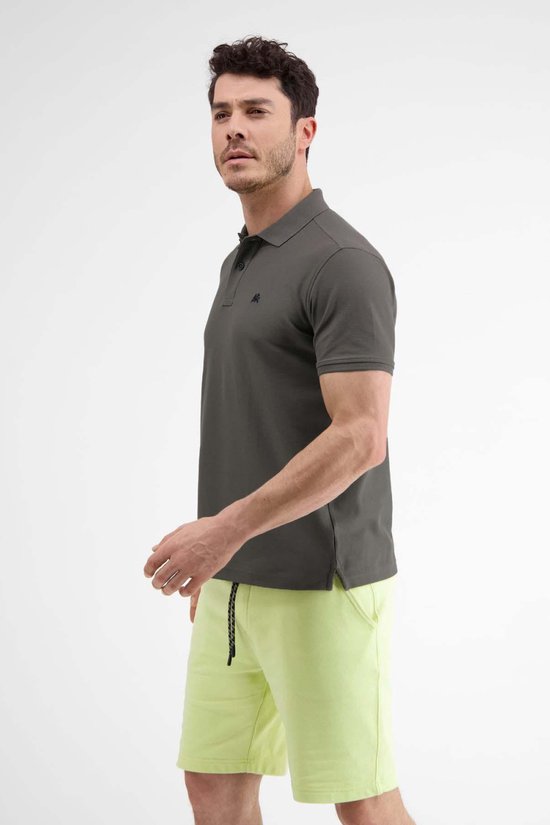 Man in donkergrijs poloshirt en lichtgroene korte broek, zicht van opzij.