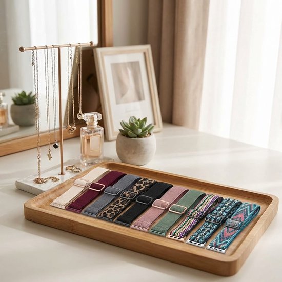 Een dressoir met een dienblad waarop tien stoffen smartwatchbandjes liggen in diverse patronen en kleuren.