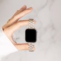 Gouden stalen bandje om een Apple Watch gedragen door een hand met witte kleding.