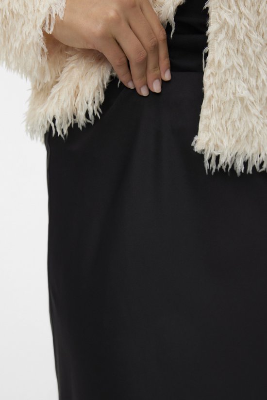 Gros plan d'une femme portant une jupe noire et un manteau pelucheux crème.