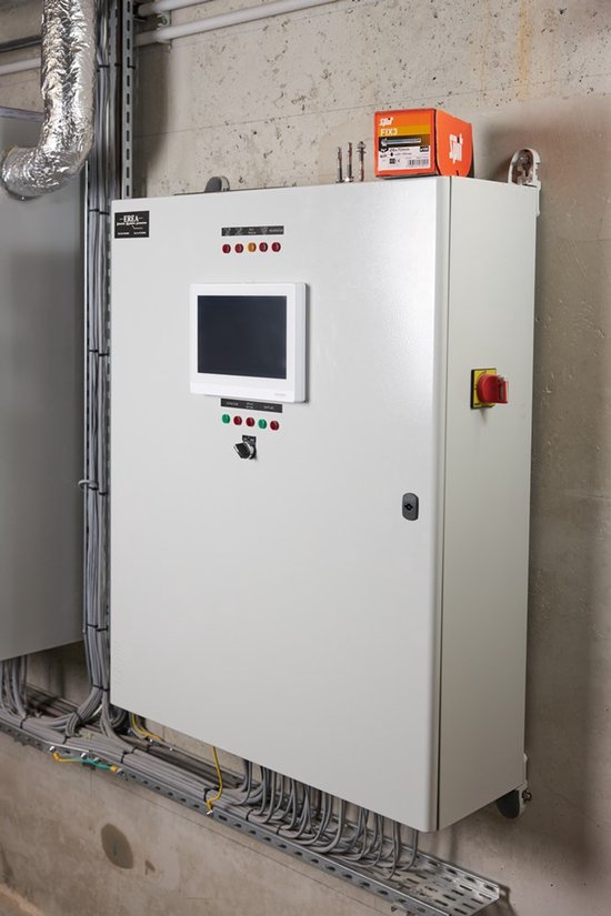Een witte elektrische kast met een scherm, knoppen en een rode noodstop, met een doos 'Spit FIX3' erbovenop.