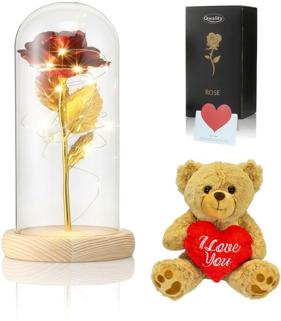 Une rose rouge dans un dôme en verre avec guirlandes LED, une boîte cadeau et un ours en peluche tenant un cœur rouge 'I Love You'.