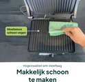 Hand veegt met groene doek over de grillplaten. "Moeiteloos schoon vegen", "Hoge kwaliteit anti-kleeflaag", "Makkelijk schoon te maken".