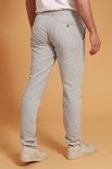 De achterkant van een man in een beige linnen broek en witte sneakers.