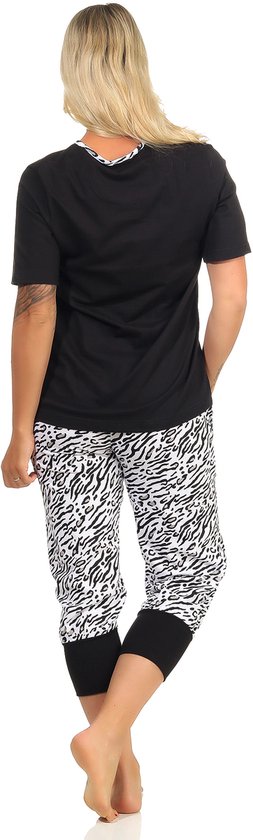 Model draagt een zwarte pyjamatop met korte mouwen en een broek met tijgerprint en zwarte manchetten.