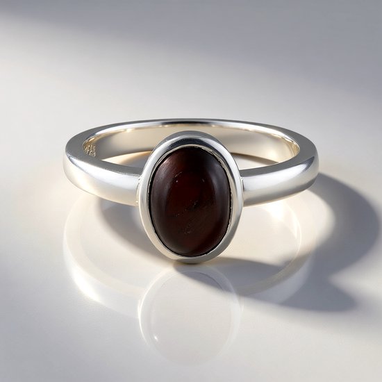 Zilveren ring met een ovale, donkerrode steen.