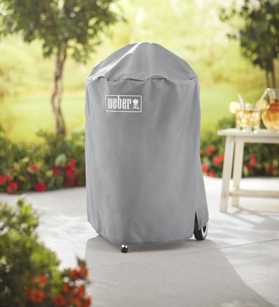 Grijze Weber barbecuehoes, geschikt voor 47 cm houtskoolbarbecues, op een terras.