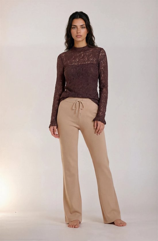 Model in bruine kanten top met lange mouwen en wijde beige broek met trekkoord.