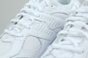 Close-up van de veters en zijdetails van een witte leren New Balance sneaker.
