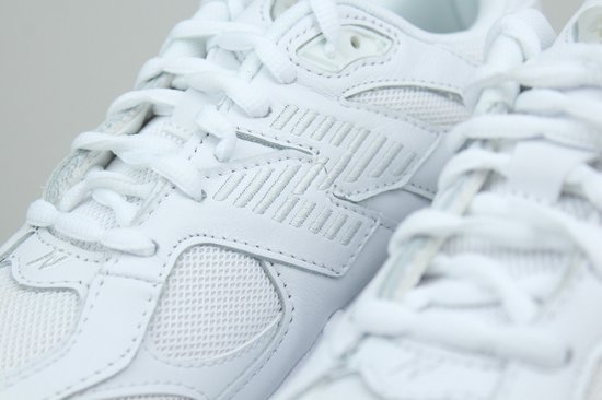 Close-up van de veters en zijdetails van een witte leren New Balance sneaker.