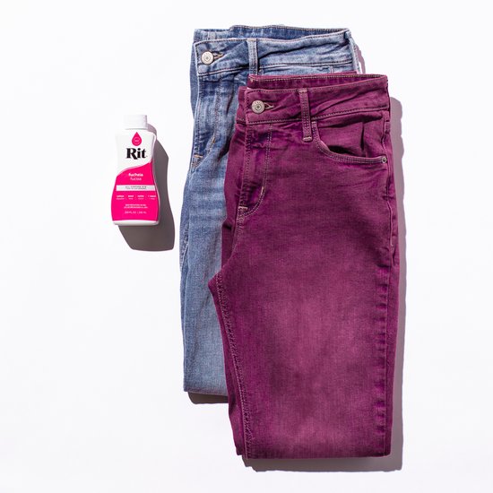 Een flesje fuchsia Rit Dye naast een lichtblauwe jeans en een fuchsia geverfde jeans.