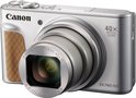 Zilverkleurige Canon PowerShot SX740 HS camera met 40x optische zoom, een bruine grip en de lens gedeeltelijk uitgeschoven.