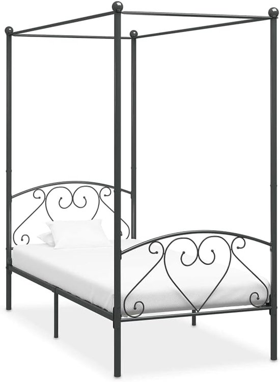 Hemelbedframe van donker metaal met hartvormige versieringen, met wit matras en kussen.