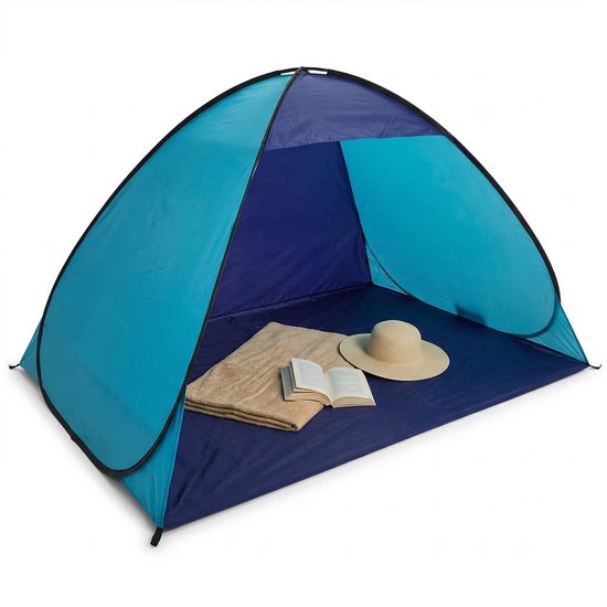 Blauwe en donkerblauwe pop-up strandtent op het strand, met handdoek, boek en strooien hoed op de grond.