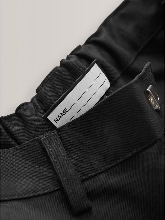 Naamlabel in de elastische tailleband van een zwarte broek.