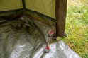 Groene tent met opgerolde ingang en rode treklussen aan de rits.