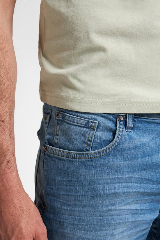 Detail van de zijkant van een lichtblauwe jeans met een lichte wassing en zichtbare stiksels.