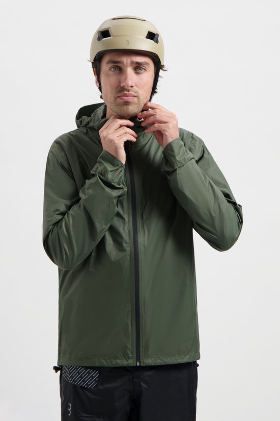 Man met helm, sluit de rits van zijn olijfgroene regenjas.