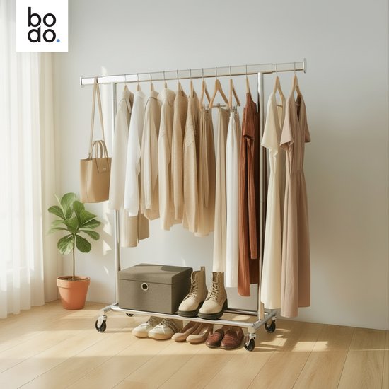 Een zilverkleurig metalen kledingrek volhangend met kleding: jassen, truien, broeken en jurken. Schoenen en tas staan op het rek.