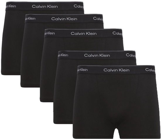 Vijf zwarte Calvin Klein boxershorts diagonaal gerangschikt, elk met witte tailleband met logo.
