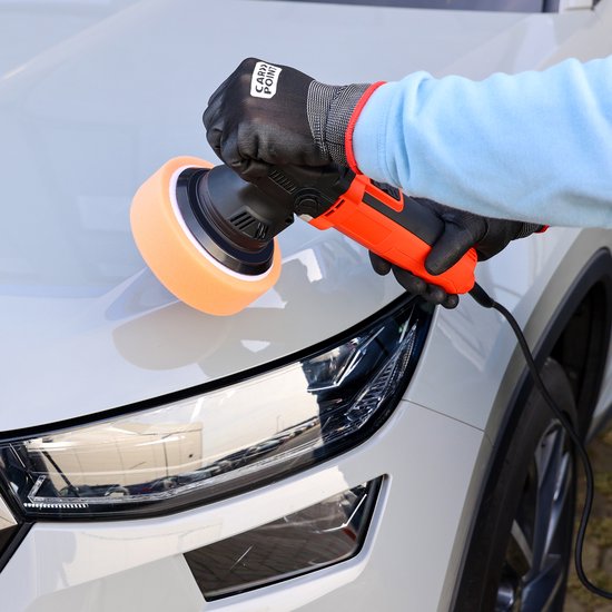 Oranje polijstmachine met oranje polijstspons wordt gebruikt op een witte auto.