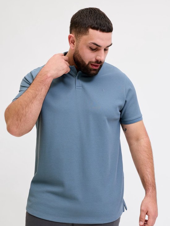 Man met baard, blauw poloshirt met korte mouwen, merklogo op borst.
