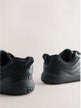 Achterkant van zwarte leren veter-sneakers, met lus aan de hiel en een golfachtig profiel op de zolen.