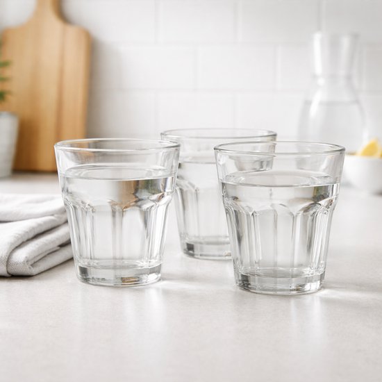 Trois verres d'eau sur un comptoir clair, avec une serviette à côté.