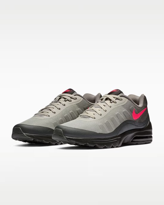Grijze Nike Air Max Invigor sneakers met roze swoosh en zwarte zolen.