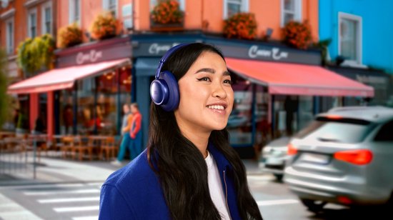 Vrouw met donkerblauwe koptelefoon op straat.