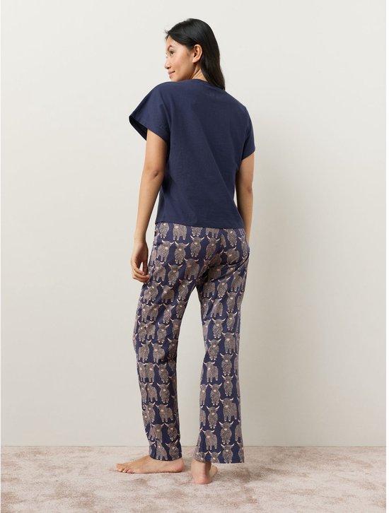 Model op de rug, draagt een marineblauwe pyjamaset met Schotse hooglanderprint.