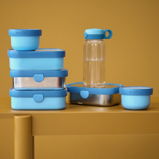 Stapel lichtblauwe Mepal lunchboxen en een waterfles met blauwe doppen.