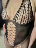 Close-up van een zwarte bodysuit met halternek, visnet en open geweven details op de buste.
