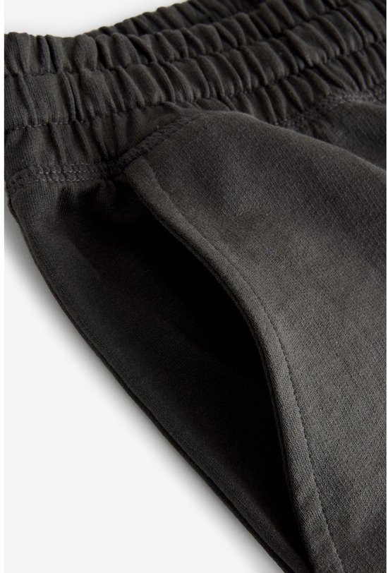 Close-up van de steekzak van een donkergrijze joggingbroek.