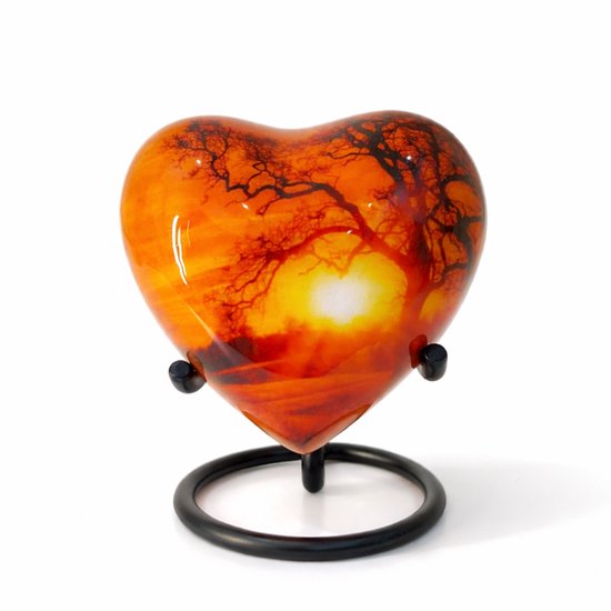 Hartvormige urn met opdruk van een zonsondergang en boom op een standaard.