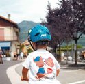 Jongen met blauwe dinosaurushelm en Paw Patrol T-shirt, gezien vanaf de achterkant.