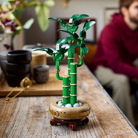 Plante de bambou LEGO sur une table en bois, tiges vertes et pot doré.