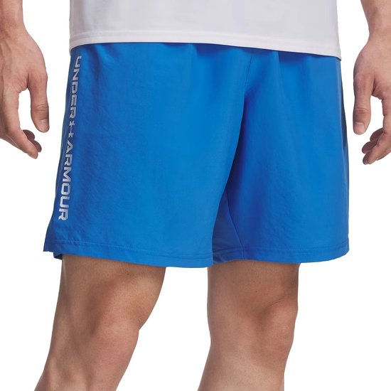 Man in een blauwe Under Armour sportbroek met 'UNDER ARMOUR' logo op de zijkant.