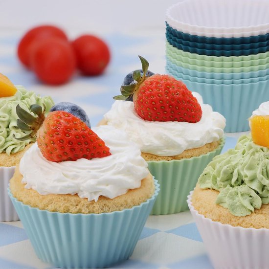 Vier cupcakes met slagroom en fruit in blauwe, groene en witte siliconen vormpjes.